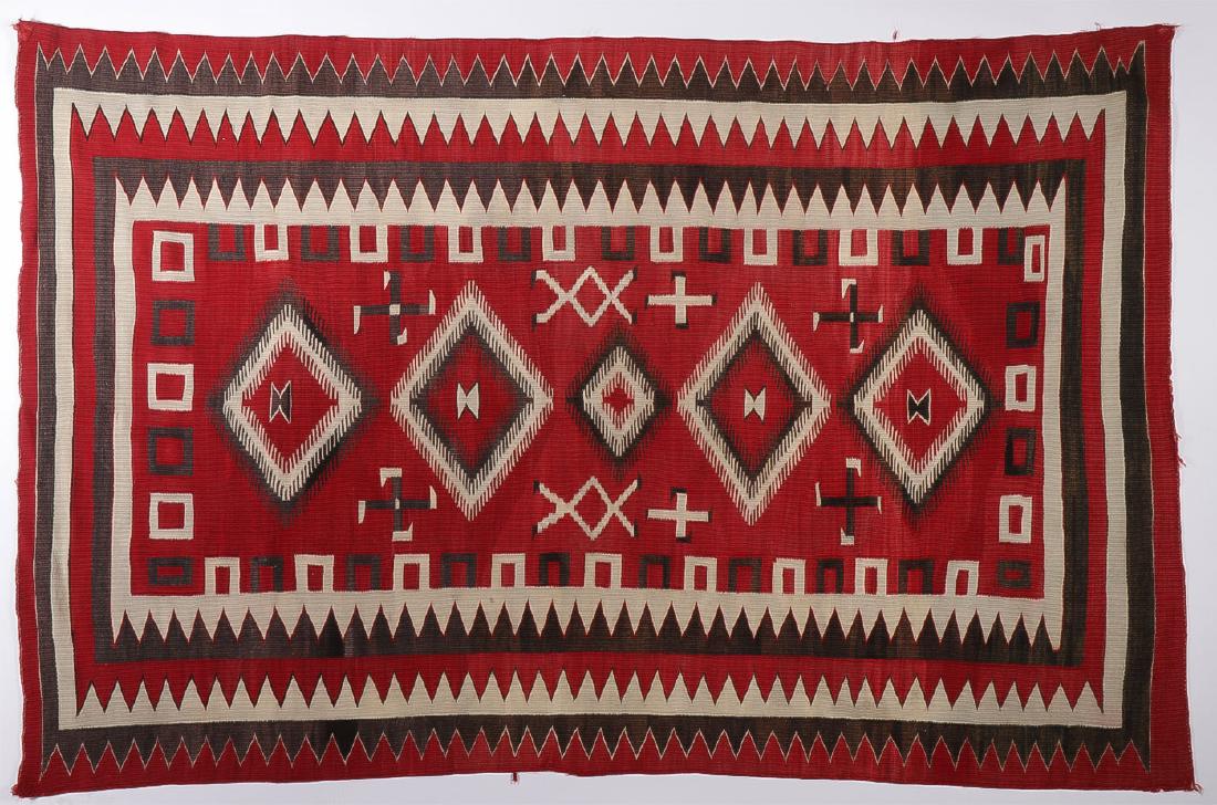 A NAVAJO RED REGIONAL RUG, C. 1935: A NAVAJO RED REGIONAL RUG, C. 1935. Of traditional design and with whirling logs. 52.5 inches x 78.5 inches. SHIPPING NOTICE: Jackson's is your sole and only source for one stop packing a