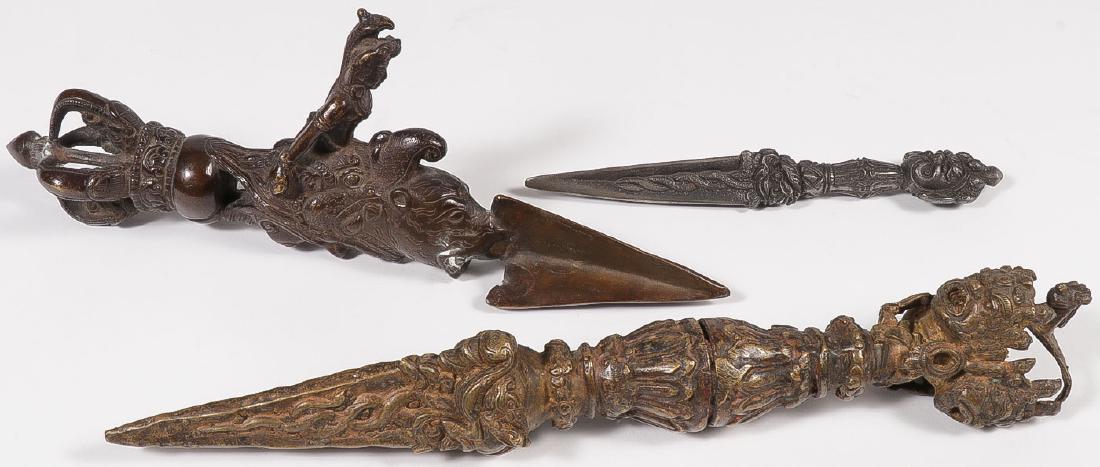 THREE INDO-TIBETAN CEREMONIAL DAGGERS: THREE INDO-TIBETAN CEREMONIAL DAGGERS. Comprising two large cast copper or bronze daggers with three sided blades and ornate handles, together with a smaller cast iron or steel example. Greatest l