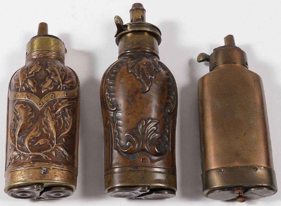 THREE DOUBLE COMPARTMENT PISTOL FLASKS, 19TH C: THREE DOUBLE COMPARTMENT PISTOL FLASKS, 19TH C. Comprising a fine large G. J. W. Hawksley Sheffield marked copper embossed flask with spring loaded lever on charger and two compartments (caps and ball