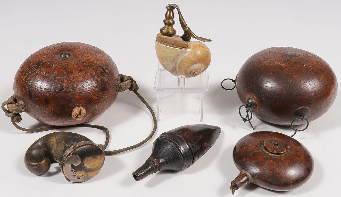 A GROUP OF CONTAINERS: A GROUP OF CONTAINERS. Comprising two heavily incised gourd flasks with lug handles and spouts, together with a shell presumably powder flask with brass spout, a small horn ink well, a horn powder fla