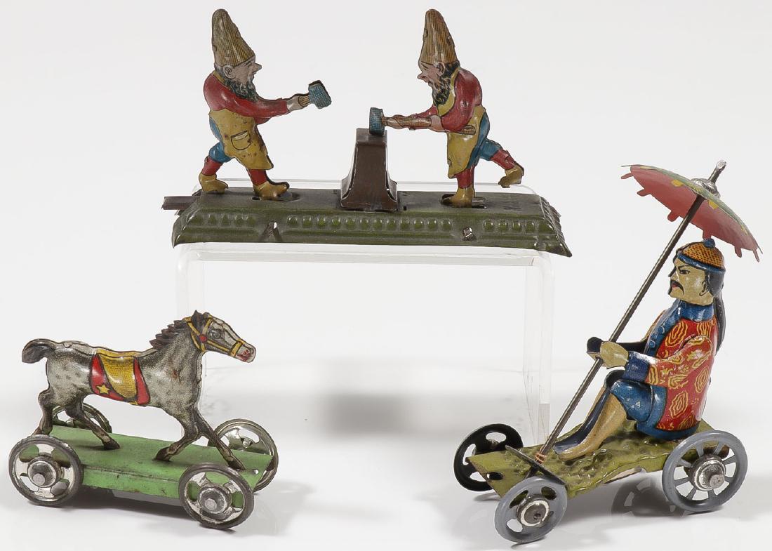 THREE GERMAN TIN PENNY TOYS: THREE GERMAN TIN PENNY TOYS. Comprising articulated gnomes hammering the same anvil. When lever is pushed, figures rock back and forth. One foot marked "GES", the other "Made in Germany