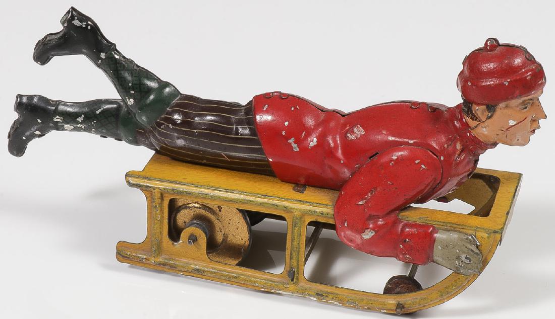 GERMAN TIN HESS BOY ON SLED: GERMAN TIN HESS BOY ON SLED. Comprising a good, functioning example with the vast majority of original finish intact. Length 6.5 inches. Provenance: From the lifetime collection of Thomas "Tom