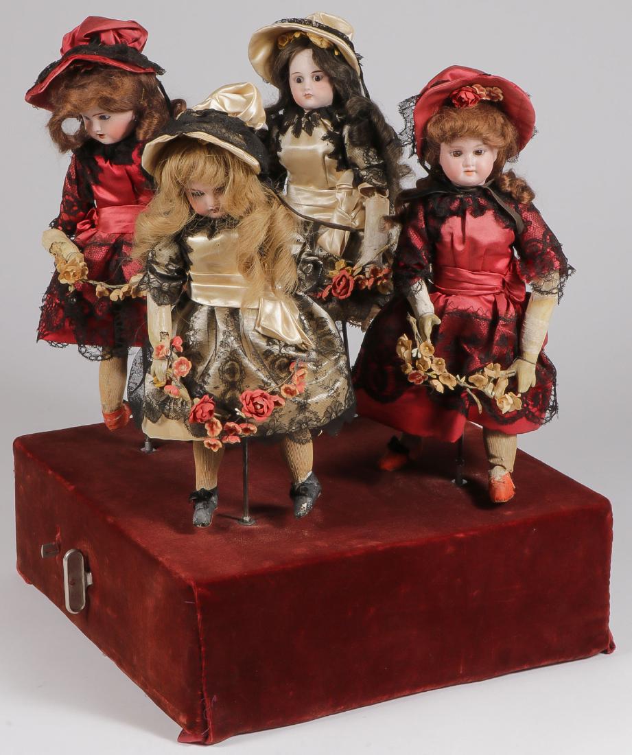 A DANCING DOLLS AUTOMATON: A DANCING DOLLS AUTOMATON. Comprising a velvet covered wooden base with key wind clockwork interior and individual key wind music box. Set with four dolls with bisque heads, glass eyes, and real hair 