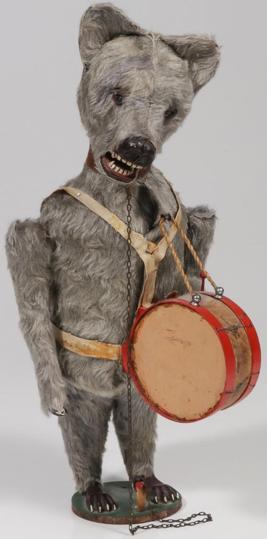 A LARGE AUTOMATON DRUMMING BEAR: A LARGE AUTOMATON DRUMMING BEAR. Comprising a large grey mohair covered standing bear with composition feet, hands snout, teeth, and glass eyes. Key wind with brass ball activation lever. Appears over