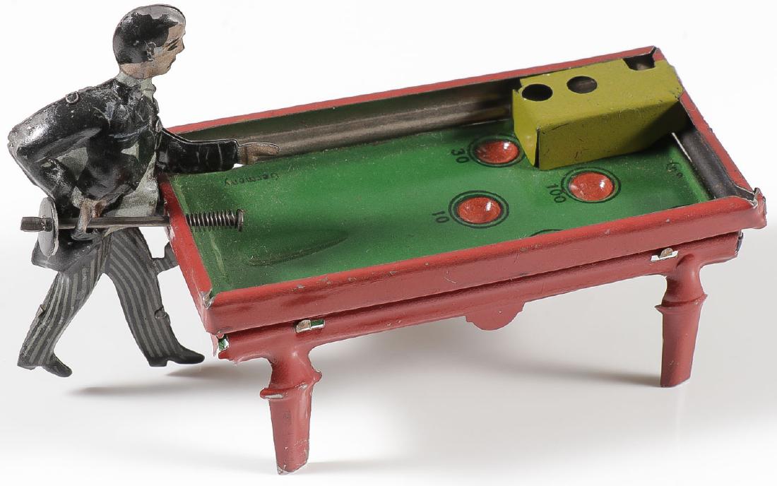 GERMAN TIN PENNY TOY BILLIARDS PLAYER: GERMAN TIN PENNY TOY BILLIARDS PLAYER. In very fine condition with original steel ball, marked "German" on the table surface. Length 4.25 inches. Together with a custom-made mirror back gl