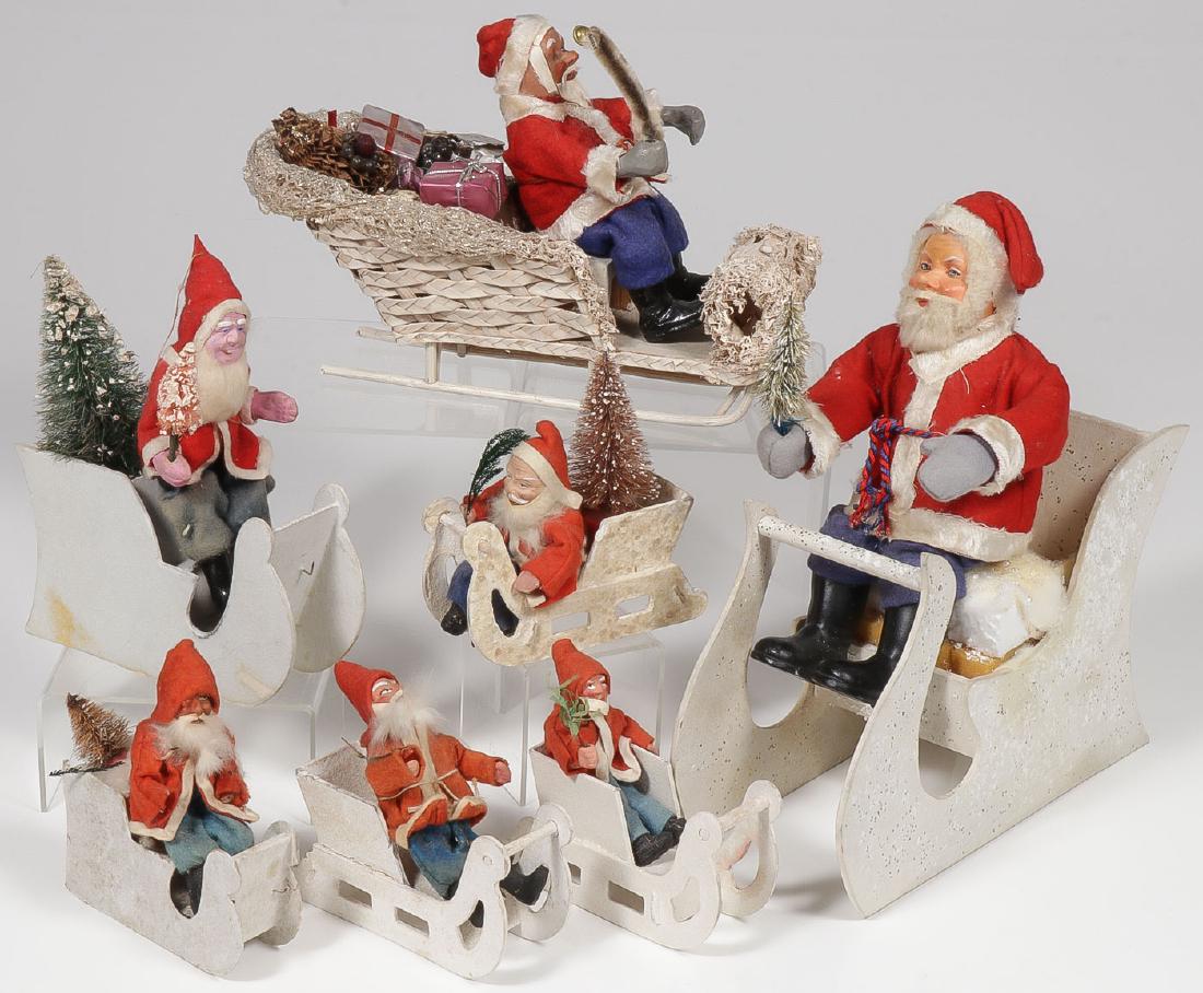 7 VINTAGE SANTAS IN SLEIGHS: 7 VINTAGE SANTAS IN SLEIGHS. Comprising a good variety, each with papier-mache or composition painted face and resting in a vintage sleigh, some examples marked Germany. Largest Santa 10 inches, l
