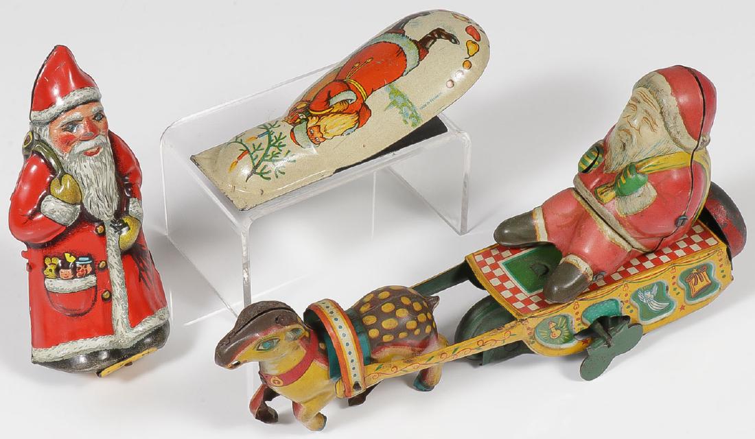 THREE VINTAGE TIN LITHO SANTAS: THREE VINTAGE TIN LITHO SANTAS. Comprising a good German Arnold key wind Santa (works), a large German tin litho Santa clicker toy (4 inches) and a Japanese tin litho wind-up Santa, sleigh, and b