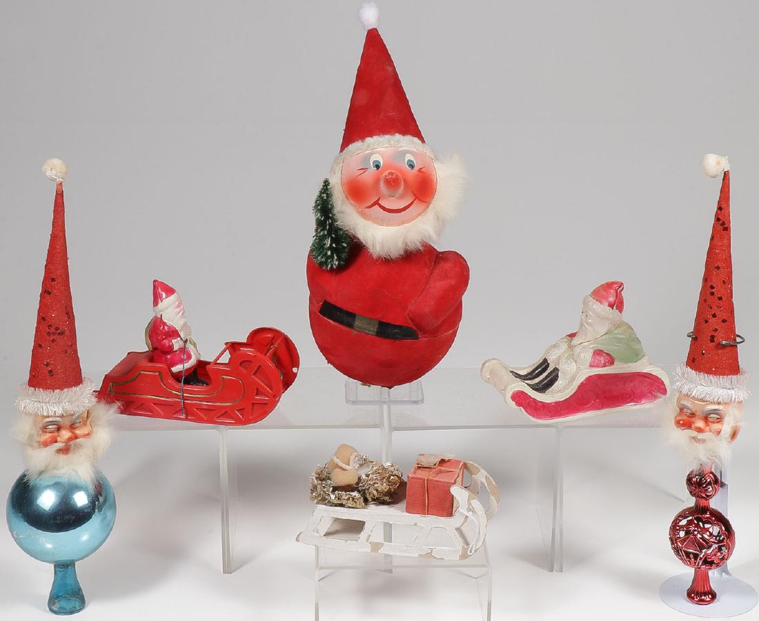 VINTAGE SANTA ORNAMENTS: VINTAGE SANTA ORNAMENTS. Comprising a large roly-poly German Santa candy container with bobble head, two Santa head Christmas tree finials, two celluloid Santas in sleigh, and a smaller German San