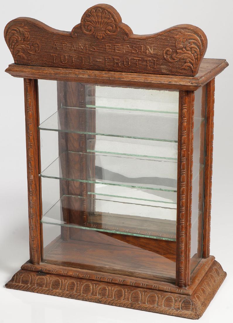 ADAMS PEPSIN TUTTI-FRUTTI OAK AND GLASS DISPLAY: AN ADAMS PEPSIN TUTTI-FRUTTI OAK AND GLASS DISPLAY CASE. A four sided rectangular countertop gum display case with hinged and mirror backed opening to reveal three glass shelves all beneath a pres