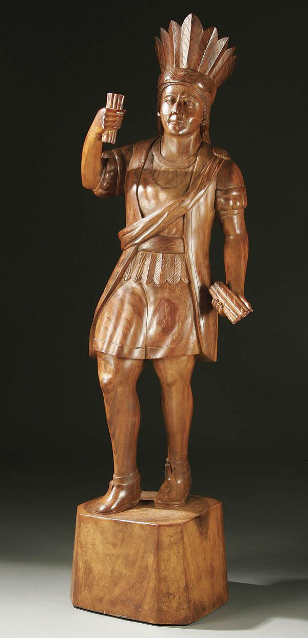 CIGAR STORE INDIAN, A CARVED SOLID WALNUT CIGAR S: CIGAR STORE INDIAN, A CARVED SOLID WALNUT CIGAR STORE INDIAN last half 20th century. Carved completely in the round holding a cigar bundle in each hand. Height 61 inches. Estimate $400-$600