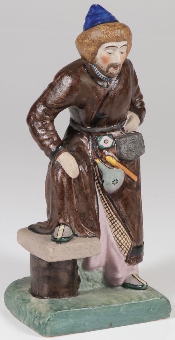 SOVIET PORCELAIN FIGURE, CIRCA 1925: A RUSSIAN BISQUE PORCELAIN FIGURE OF A BASHKIR, C. 1925. Finely modelled in full round and in Bashkir attire with corresponding accoutrements. Apparently unmarked, perhaps Dmitrievsky and likely from 