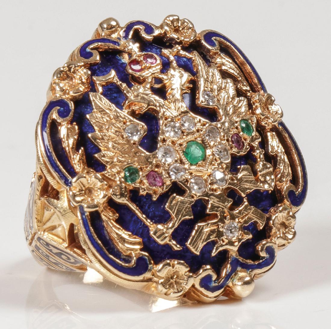 GOLD AND GEM SET IMERIAL RUSSIAN STYLE RING: A GOLD AND GEM SET ENAMELED IMPERIAL RUSSIAN COURT STYLE RING, POSSIBLY C. 1915. The ornate gold setting with open work borders and the upper band in ChamplevÉ enamel with shaped shield form sign