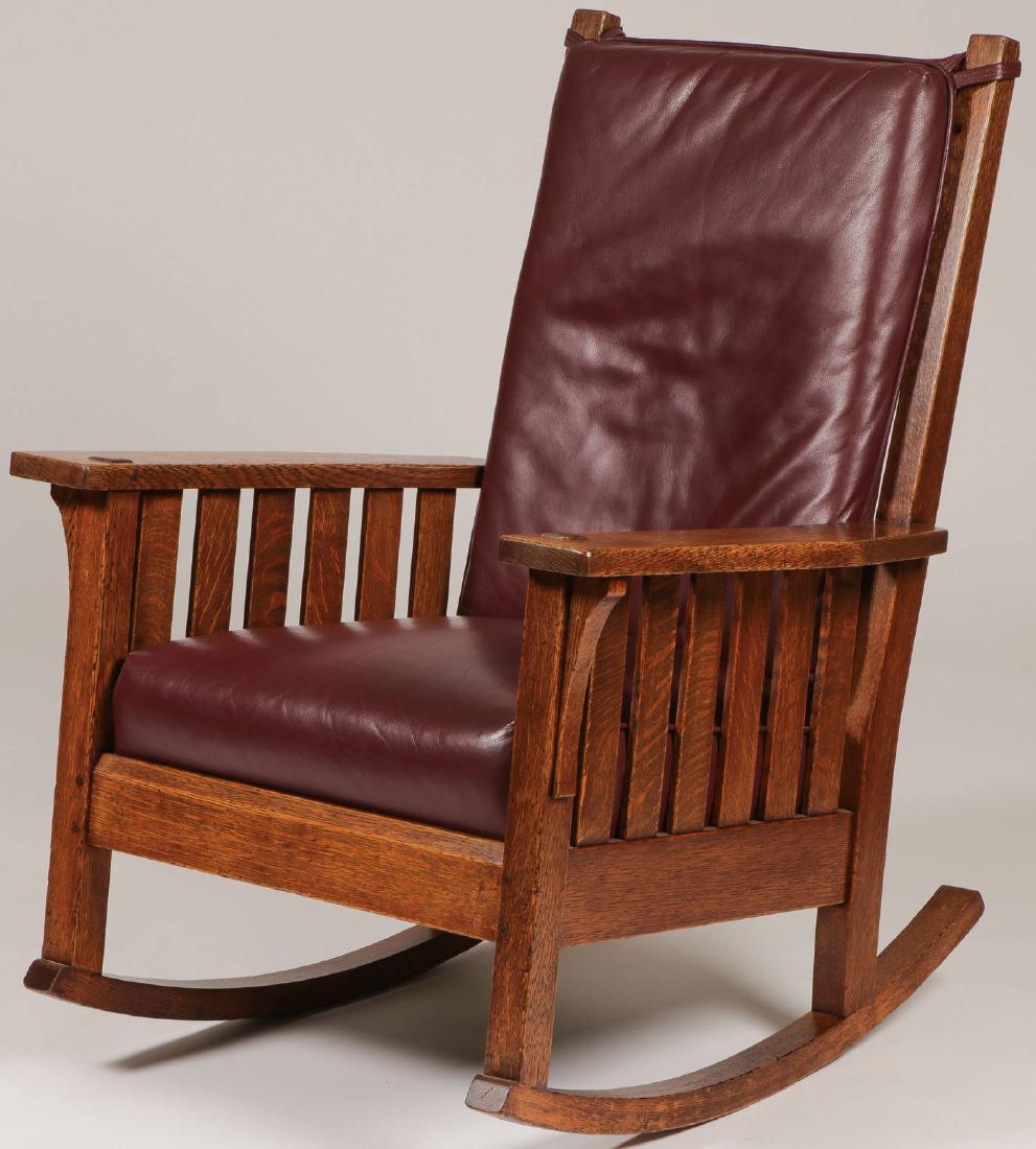 L & JG STICKLEY ROCKER #451: L & JG STICKLEY ROCKER #451. Comprising a high back rocker with six vertical slats at back and under each arm and corbel supports at sides. With two line maker's brand. Upholstered in later red leathe
