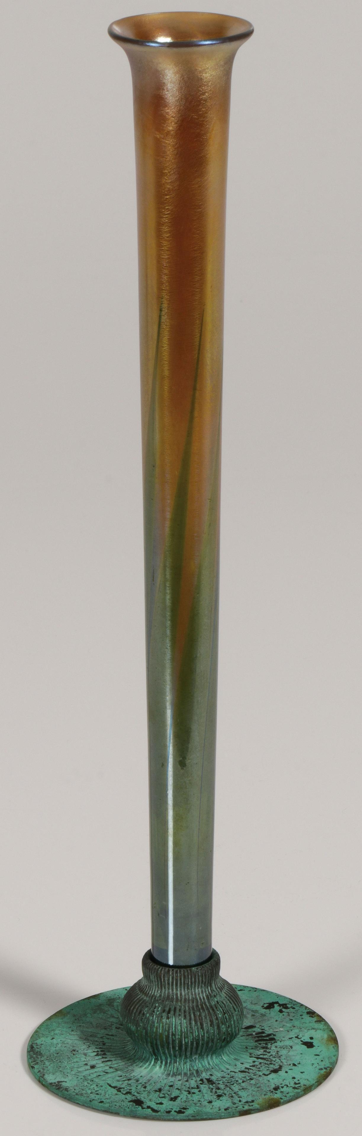 TIFFANY FAVRILE & BRONZE BUD VASE: TIFFANY FAVRILE & BRONZE BUD VASE. Comprising a Tiffany Favrile art glass vase signed L. C. T. and resting in a bronze with verdigris patina base with rib bulb form socket, underside of base marked TI