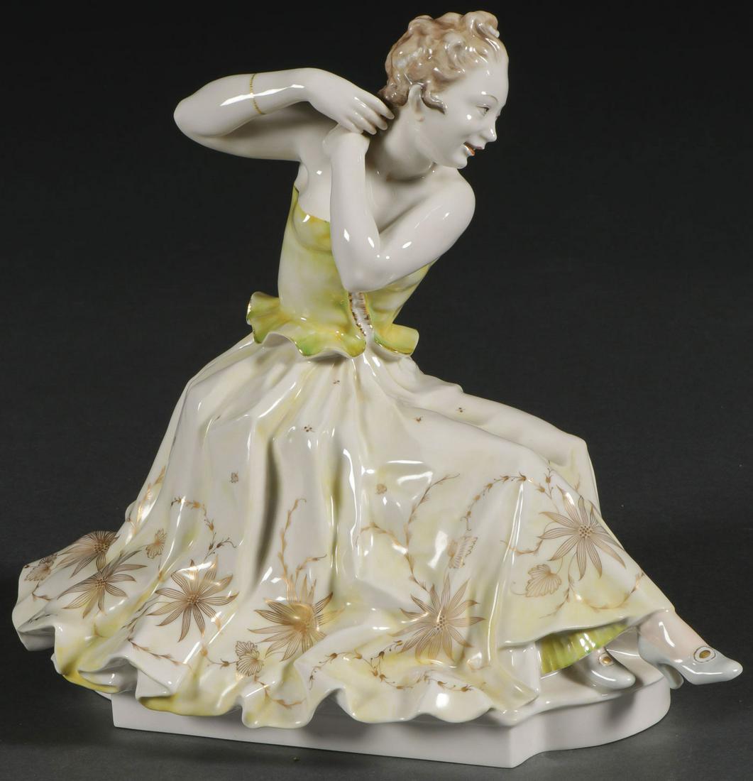 A HUTSCHENREUTHER PORCELAIN FIGURE: A HUTSCHENREUTHER PORCELAIN FIGURE. Comprising a porcelain figure of a seated woman in a formal dress with floral decoration fixing her hair. Markers mark on bottom. Height 10 inches. SHIPPING NOTICE: