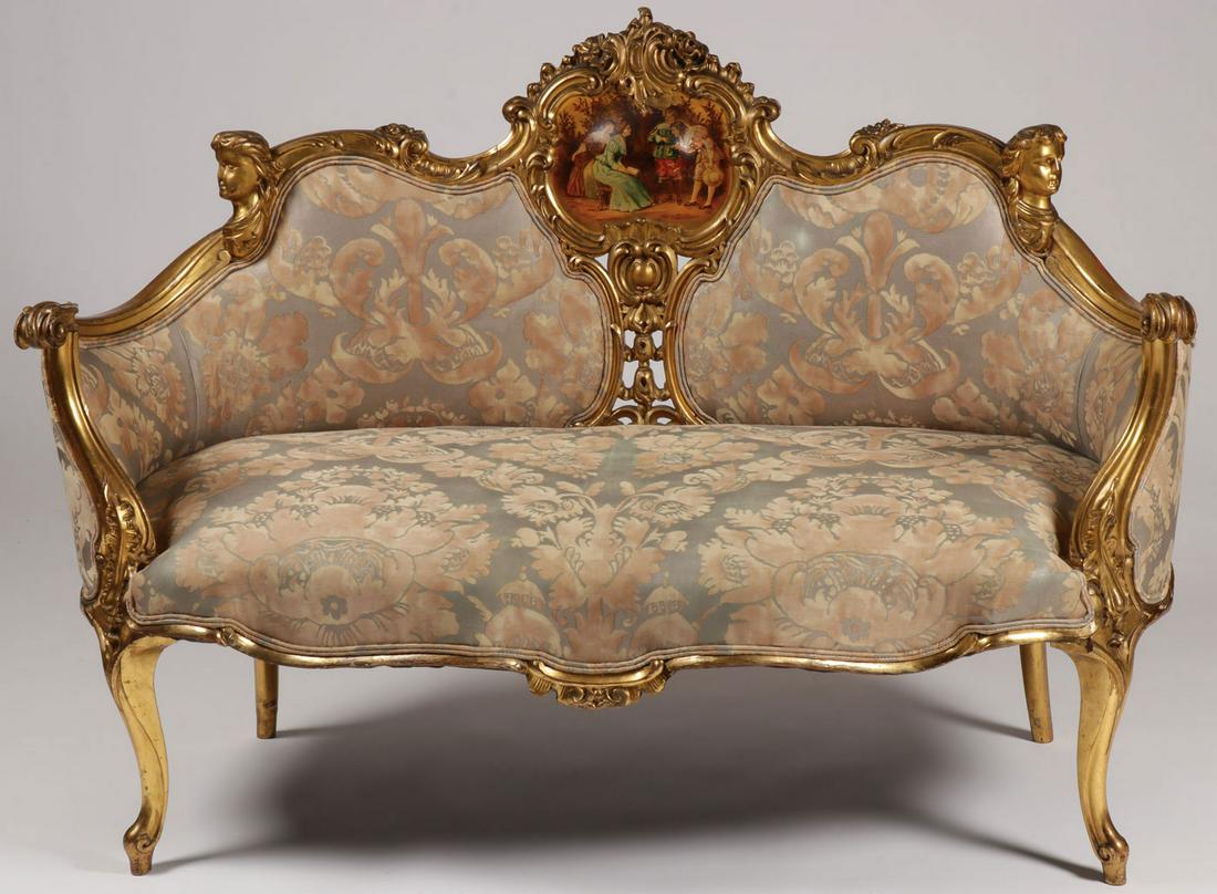 A LOUIS XV STYLE CARVED GILT WOOD SETTEE, C. 1920: A LOUIS XV STYLE CARVED GILT WOOD SETTEE, C. 1920. Comprising a gilt wood frame carved throughout depicting faces and flowers with scrolled arm rest giving way to reverse scrolled legs. The seat and