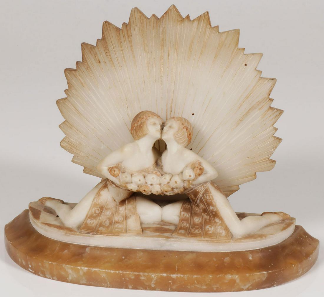 AN ART DECO ALABASTER CARVED LAMP: AN ART DECO ALABASTER CARVED LAMP. Comprising a carved and stained alabaster lamp depicting two Art Deco kneeling women in front of a sunburst on shaped based. The interior with illuminated socket. He