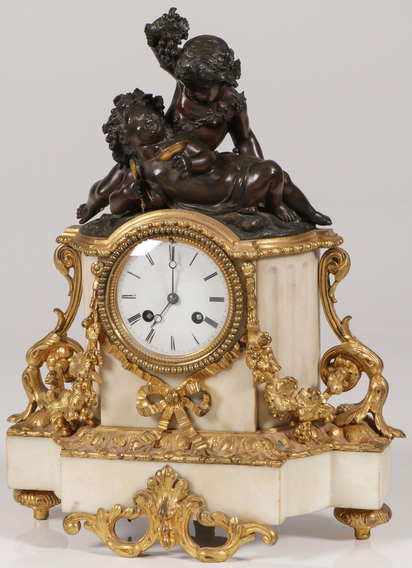 A FRENCH ORMOLU MARBLE & BRONZE MANTLE CLOCK: A FRENCH ORMOLU MARBLE & BRONZE MANTLE CLOCK. Comprising a mantle clock of traditional form set with a bronze figural depiction of bacchanal putti above an enamel dial with roman numerals and ormolu d