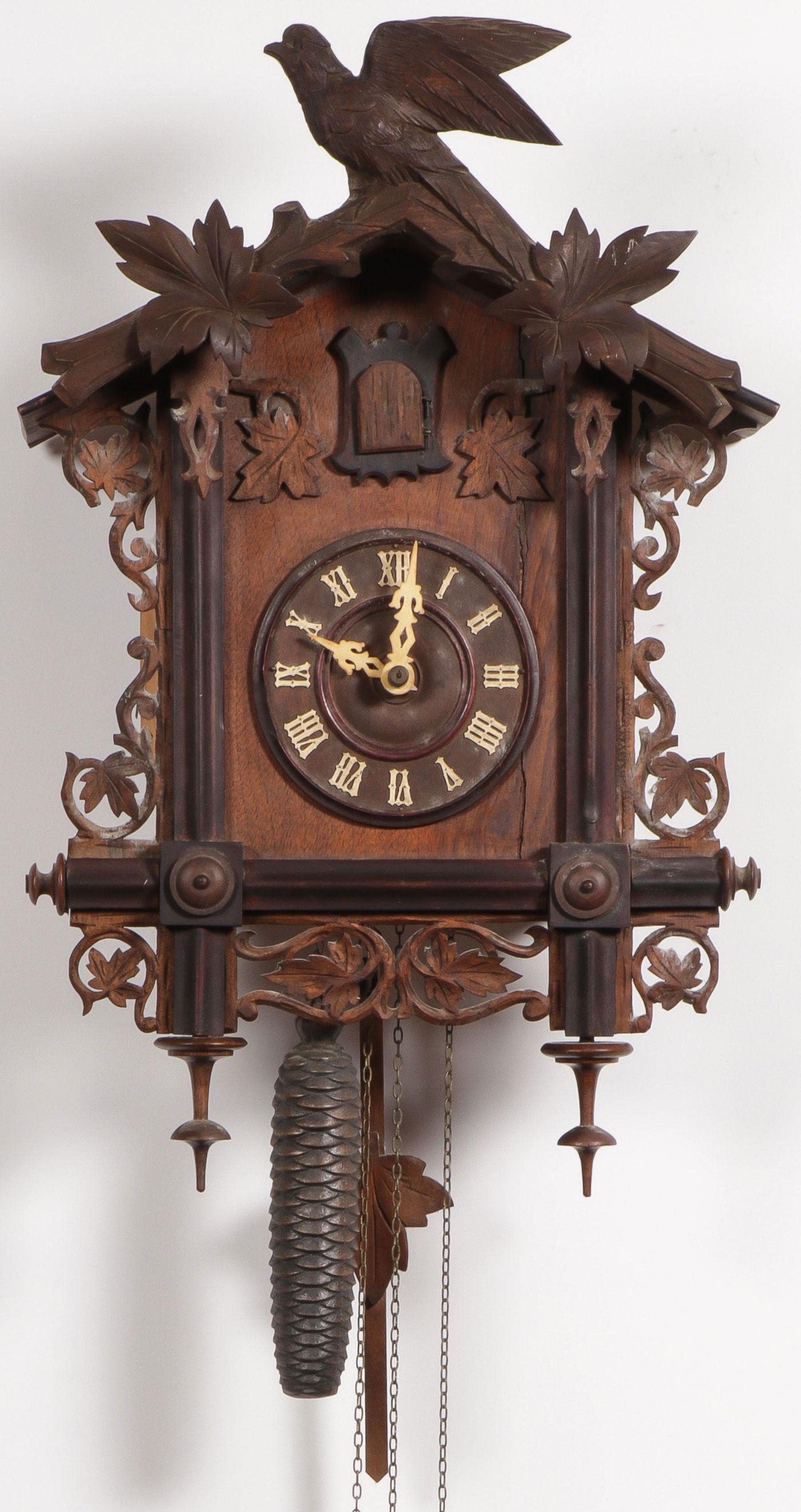 A GERMAN CUCKOO CLOCK, C. 1900: A GERMAN CUCKOO CLOCK, C. 1900. Comprising a German Black Forest cuckoo clock with ornate bird and foliage carvings, a wood dial with roman numerals, a small cuckoo, and pinecone weights. Height 20.5 