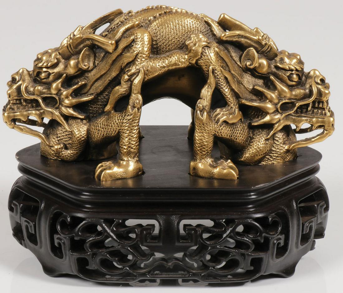 A FINE CHINESE GILT BRONZE SCROLL WEIGHT: A FINE CHINESE GILT BRONZE SCROLL WEIGHT. Finely sculpted with exceptional detail and depicting a double headed serpentine dragon set upon a conforming carved wood stand. Length 5.5 inches (14 cm). SH