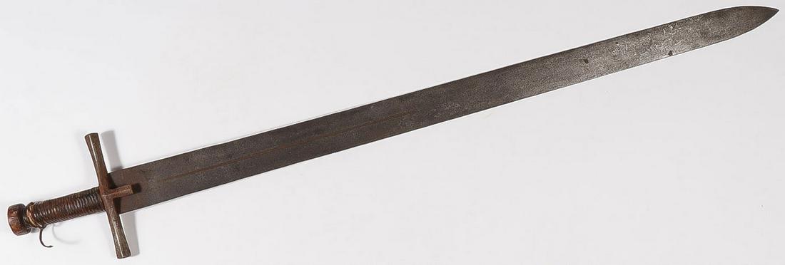 A LARGE SUDANESE KASKARA: A LARGE SUDANESE KASKARA. With long double edged single fuller blade with traditional T-guard and leather wrapped handle. Length 39.25. SHIPPING NOTICE: Jackson's is your sole and only source f