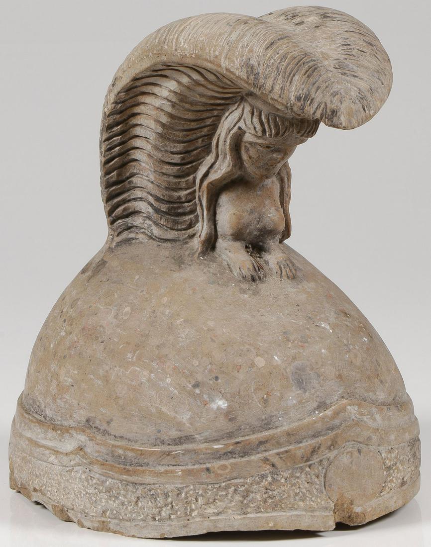 A CARVED STONE HELMET: A CARVED STONE HELMET. Comprising a life-size carved stone helmet with sphynx and plumage and ornate banding on rim. Height 11 inches (28 cm).SHIPPING NOTICE: Jackson's is your sole and only sou