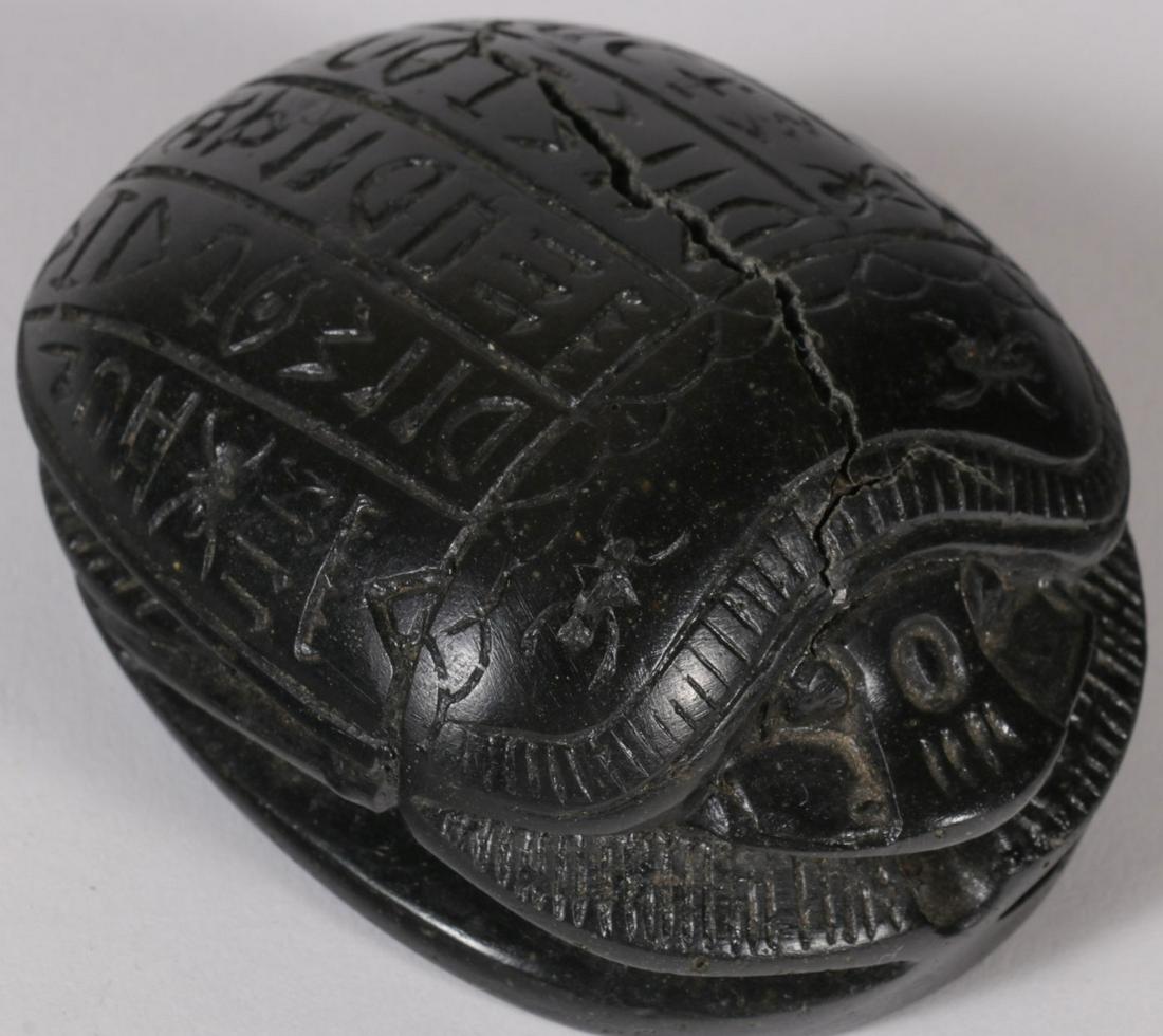 AN INTERESTING SCARAB: AN INTERESTING SCARAB. Of heavy black material (stone?) of traditional form, the underside smooth, the shell carved with rows of hieroglyphics. Age unknown. Length 3 inches (7.5 cm).SHIPPING NOTICE: