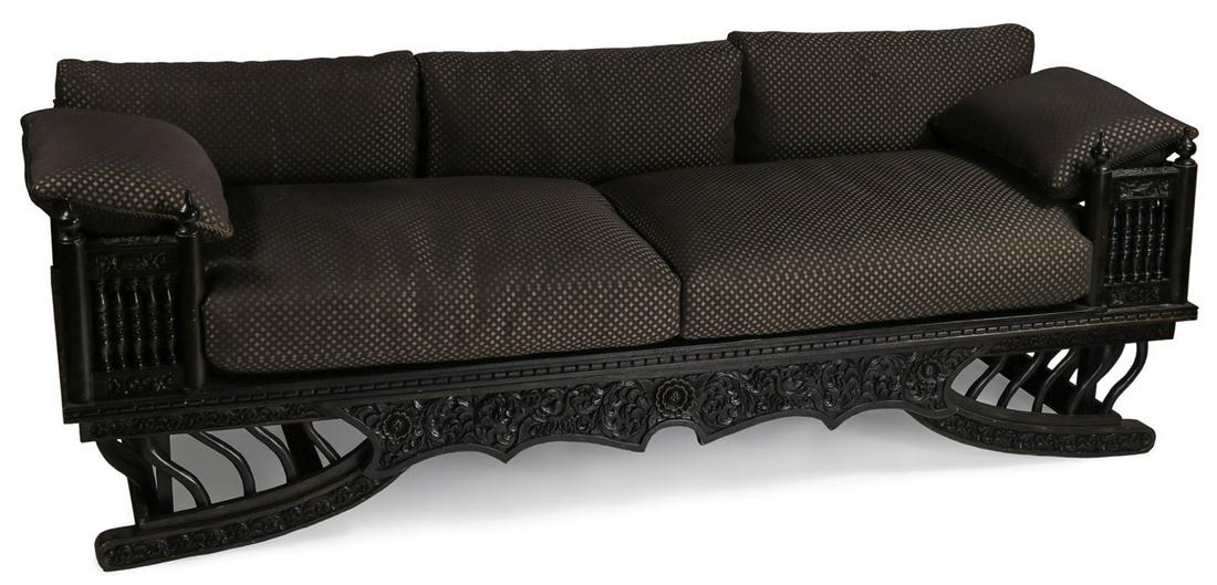 A LARGE CARVED WOOD HOWDAH STYLE THAI SOFA: A LARGE CARVED WOOD HOWDAH STYLE THAI SOFA. Finely carved with turned baluster railing, relief carved skirt, and splayed front legs with conforming modern cushions.Â Height 29 inches (74 cm), lengt