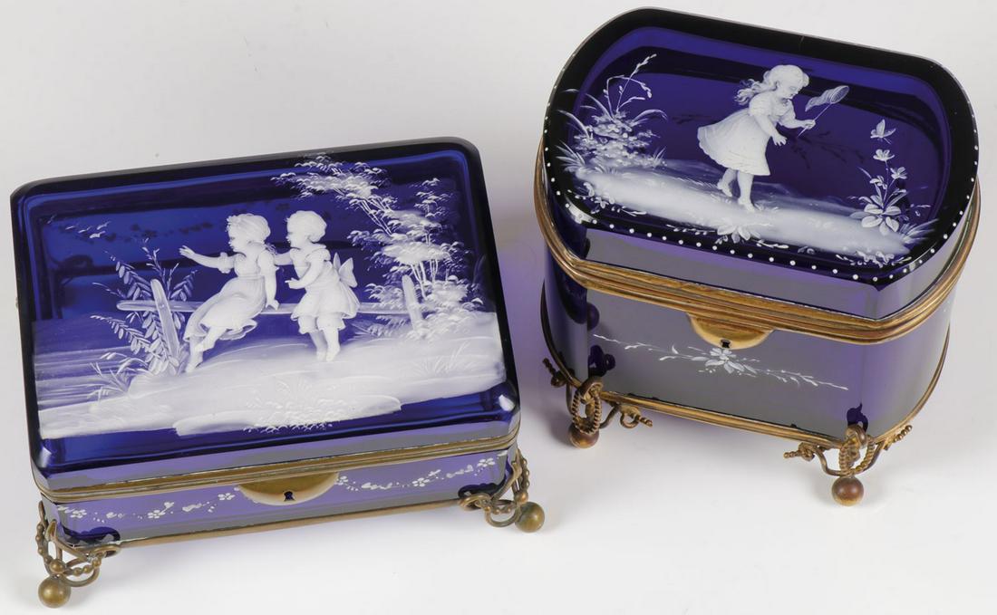 TWO MARY GREGORY COBALT BOXES, C. 1880: TWO MARY GREGORY COBALT BOXES, C. 1880. Comprising two exceptional Bohemian (AKA Mary Gregory) enamel decorated cobalt blue glass boxes. Each in metal stands with ball feet, the tallest of the two wit