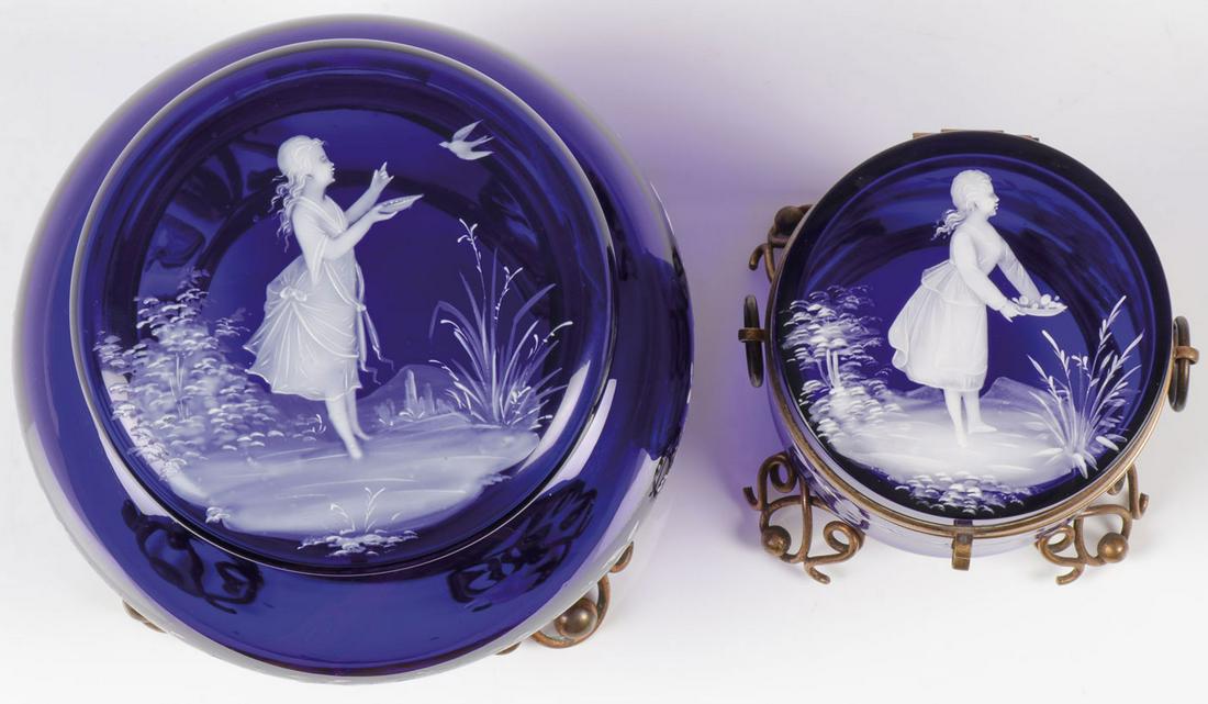 TWO COBALT MARY GREGORY BOXES, C. 1890: TWO COBALT MARY GREGORY BOXES, C. 1890. Comprising two Bohemian (AKA Mary Gregory) enamel decorated cobalt blue glass boxes. The largest specimen on gilt wire and ball feet, the hinged lid finely pain