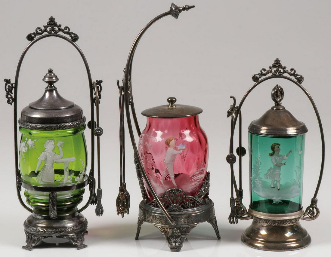 MARY GREGORY PICKLE CASTERS: MARY GREGORY PICKLE CASTERS. Comprising three Victorian pickle casters with Bohemian (AKA Mary Gregory) decorated inserts including cranberry, emerald green, and sapphire blue, and each contained in a