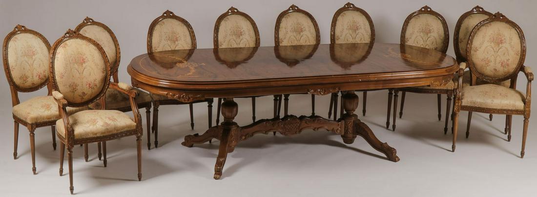 IMPRESSIVE CARVED DINING ROOM SET: IMPRESSIVE CARVED DINING ROOM SET. Comprising a large and impressive oval table with inlaid marquetry floral swags at both ends above a carved frieze resting on a four-legged base comprising two balu