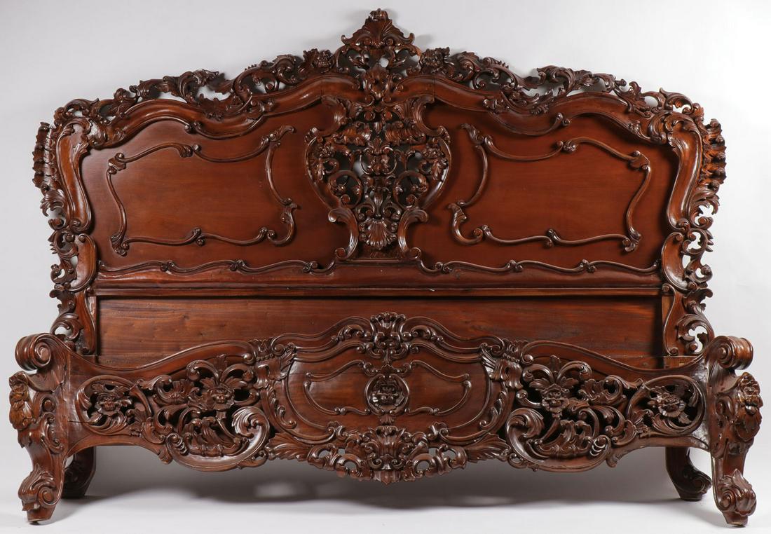 FINE CARVED MAHOGANY KING SIZE BED 20TH C: A SPECTACULAR CARVED MAHOGANY KING SIZE BED, 2ND HALF 20TH C. The headboard with ornately pierce carved central floral crests of rocaille scrolls, beneath a similarly carved border, and a similarly c