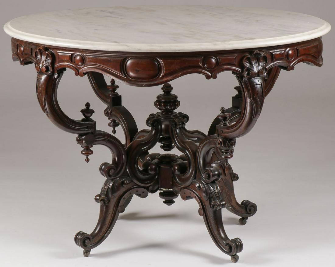 A ROCOCO REVIVAL WALNUT PARLOR TABLE, 19TH C: A ROCOCO REVIVAL WALNUT PARLOR TABLE, 19TH C. Comprising an ornate carved walnut table with oval marble top over oval scalloped frieze resting on double c-scroll legs with conforming stretcher. Height