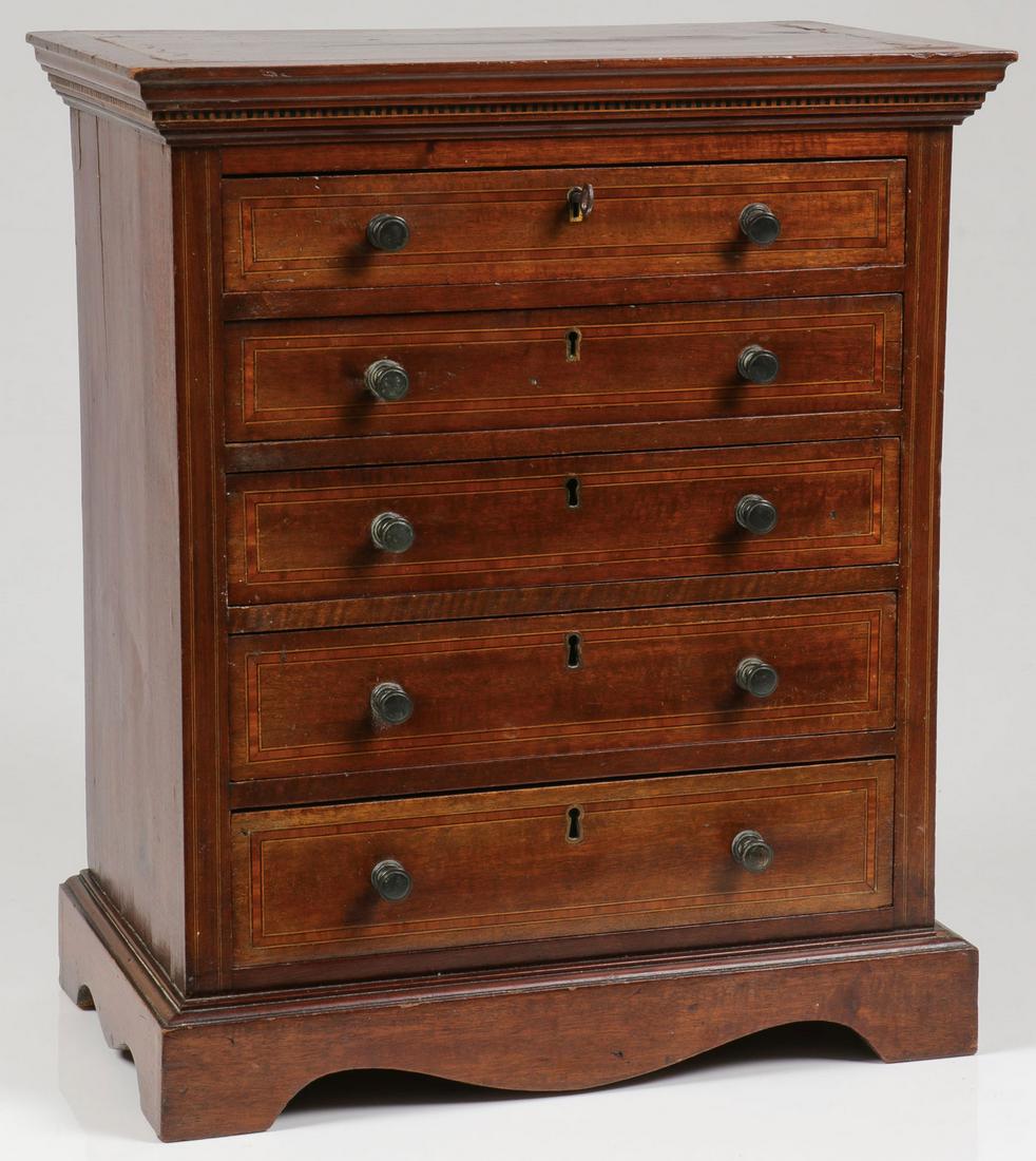 MAHOGANY MINIATURE CHEST, 19TH C: MAHOGANY MINIATURE CHEST, 19TH C. Resting on bracket feet, the five-drawer chest with matching pulls beneath an overhanging cornice and with inlaid decorative elements. Height 19.25 inches, width 16.5