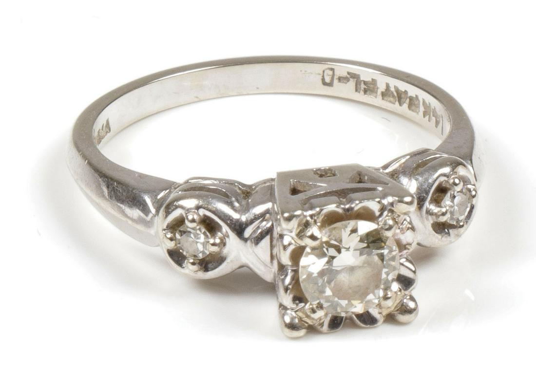 A WOMEN'S HALF CARAT DIAMOND SOLITAIRE RING: A WOMEN'S HALF CARAT DIAMOND SOLITAIRE RING. Comprising a women's approximately half carat brilliant cut solitaire diamond set in a 14kt white gold mount with two smaller round cut diamonds mounted on