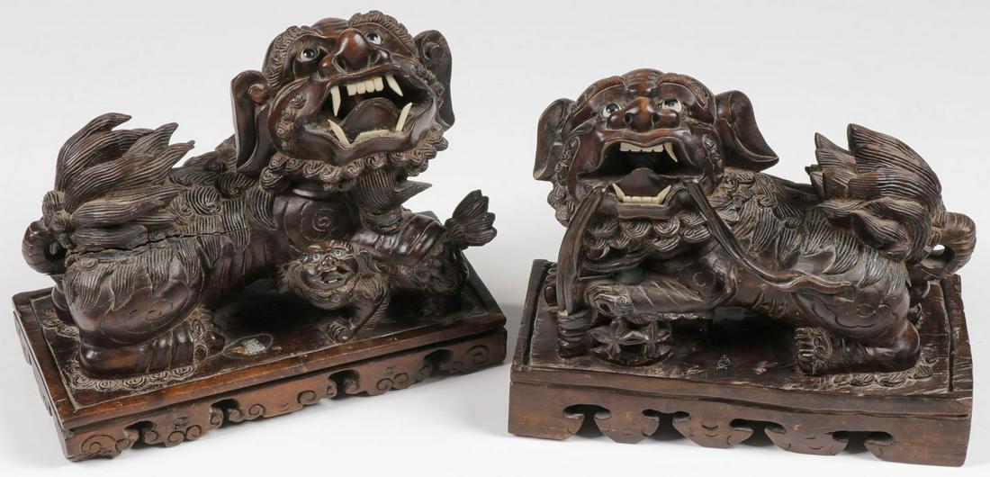 CHINESE CARVED WOOD FOO DOGS: CHINESE CARVED WOOD FOO DOGS. Comprising a pair of finely carved opposing foo dogs, set on integral footed bases, carved in full round, with exceptional detailing, the heads set with glass eyes and th