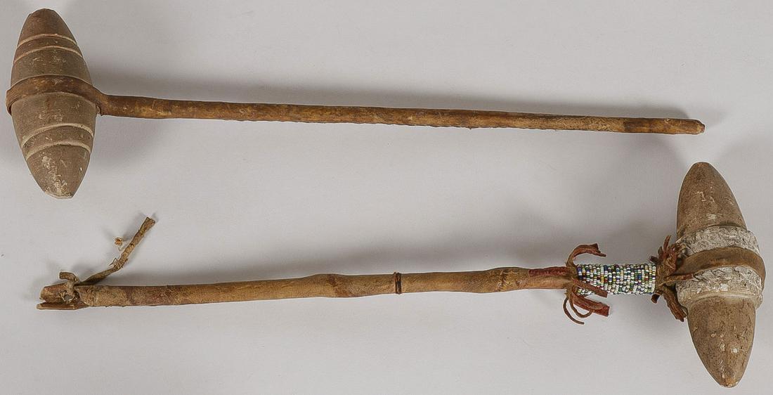 TWO PLAINS INDIAN WAR CLUBS: TWO PLAINS INDIAN WAR CLUBS. Comprising two traditional polished stone war clubs on hide wrapped wood hafts, one with beaded collar. First quarter 20th century. Greatest length 17 inches. SHIPPING NOT