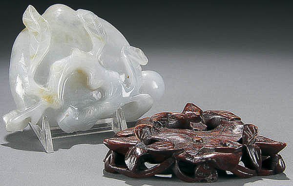 A CHINESE CARVED JADE COUPE early 20th century, w: A CHINESE CARVED JADE COUPE early 20th century, with russet markings displayed on a matching carved rosewood stand. Length 4 inches. Estimate $100-$200