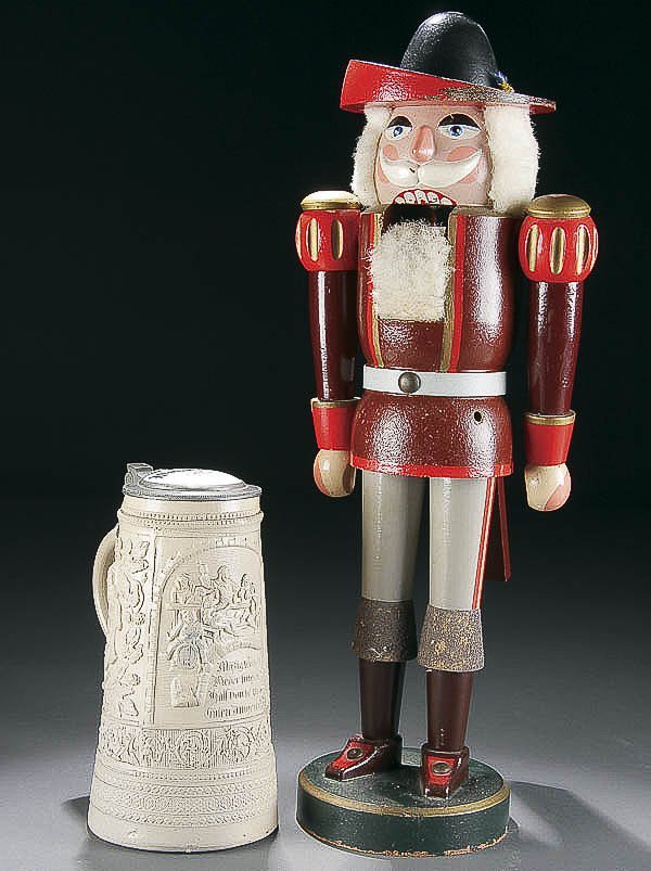 GERMAN STONEWARE STEIN & WOOD NUT CRACKER: A GERMAN STONEWARE STEIN AND EAST GERMAN CARVED WOOD NUT CRACKER circa 1900 and 1950, the salt glaze stein with Beer Hall slogans, the polychrome nut cracker missing sword. Height 9 inches and 21 inch