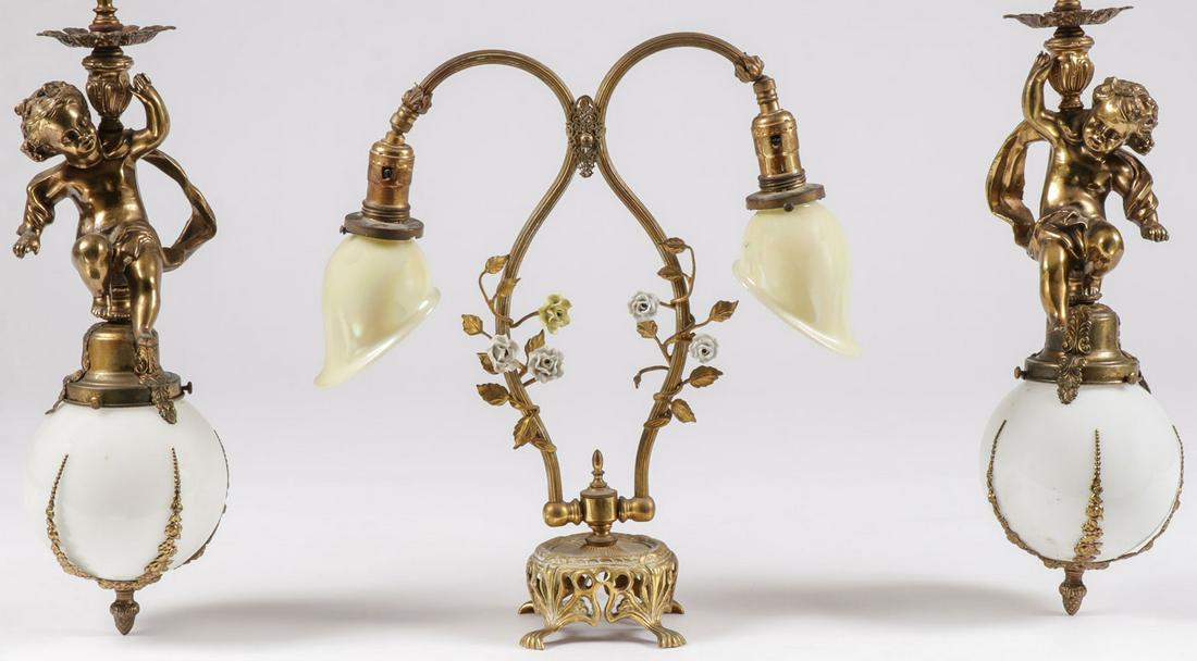LIGHTING GROUP: LIGHTING GROUP. Comprising a double light brass table lamp with porcelain flowers and glass shades (center), height 17.75 inches, and a pair of matching figural hanging lamps in bronze metal, depictin