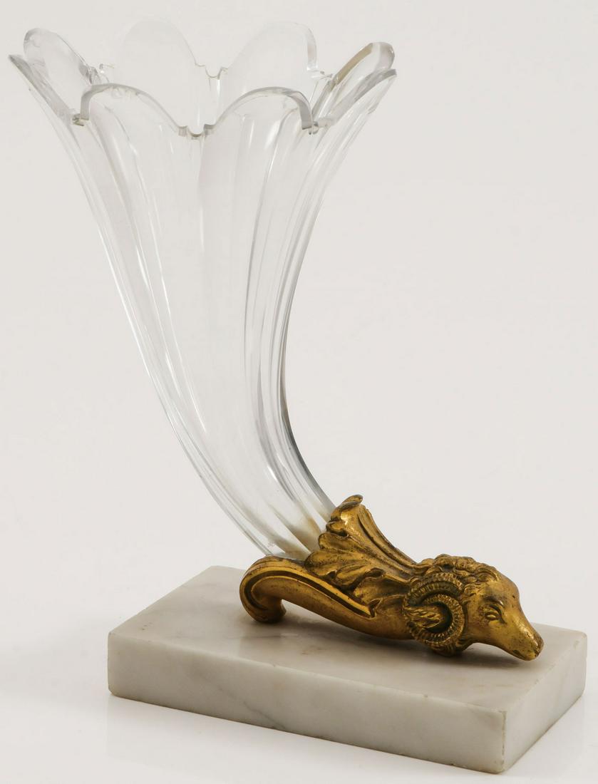 A FRENCH ORMOLU MOUNTED VASE: A FRENCH ORMOLU MOUNTED VASE. Comprising a finely shaped crystal trumpet shaped vase set in a finely sculpted gilt bronze ram's head and acanthus leaf holder set on square polished marble base, 19th c