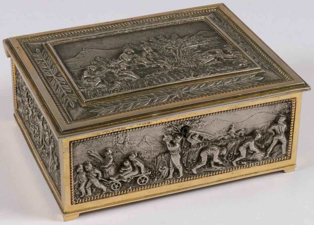 A SILVERED AND GILT METAL JEWELRY BOX C. 1920: A SILVERED AND GILT METAL JEWELRY BOX C. 1920. Of slightly rectangular form resting on raised feet on each corner, the sides with finely sculpted relief panels of wine making and other harvesting scen