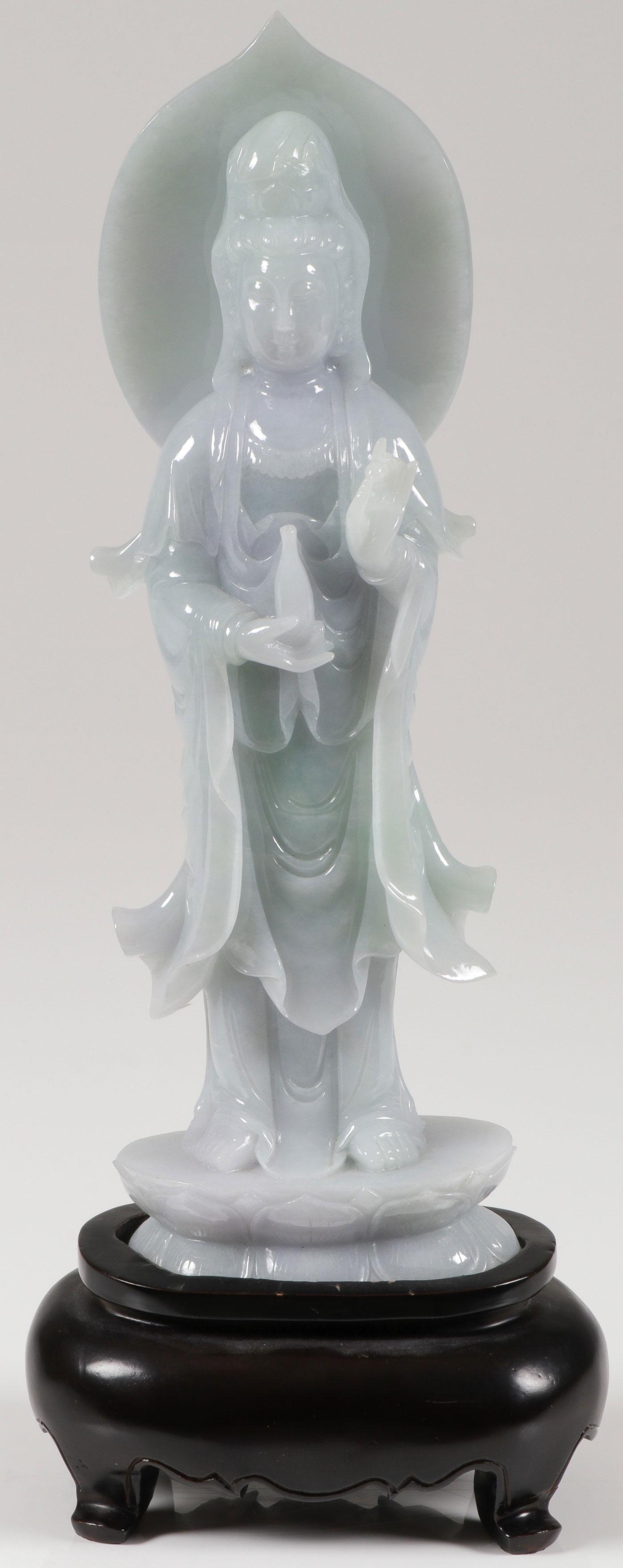 A CHINESE CARVED JADE KWAN YIN: A CHINESE CARVED JADE KWAN YIN. Carved in full round standing on a double lotus base holding a bottle and a pearl, with deep folds, good proportions and anatomy, and resting on a conforming wood base.