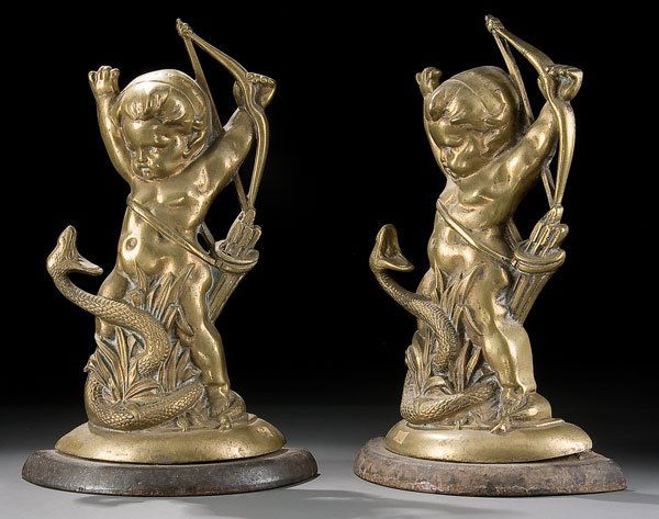 Pair English Victorian andirons: A PAIR OF ENGLISH VICTORIAN BRONZE ''CUPID AND SNAKE'' FIGURAL ANDIRONS circa 1900. Depicting the infant cupid warding off a coiled snake, raised on a cast iron base. Height 15.75 inches, 40.5 cm. Est