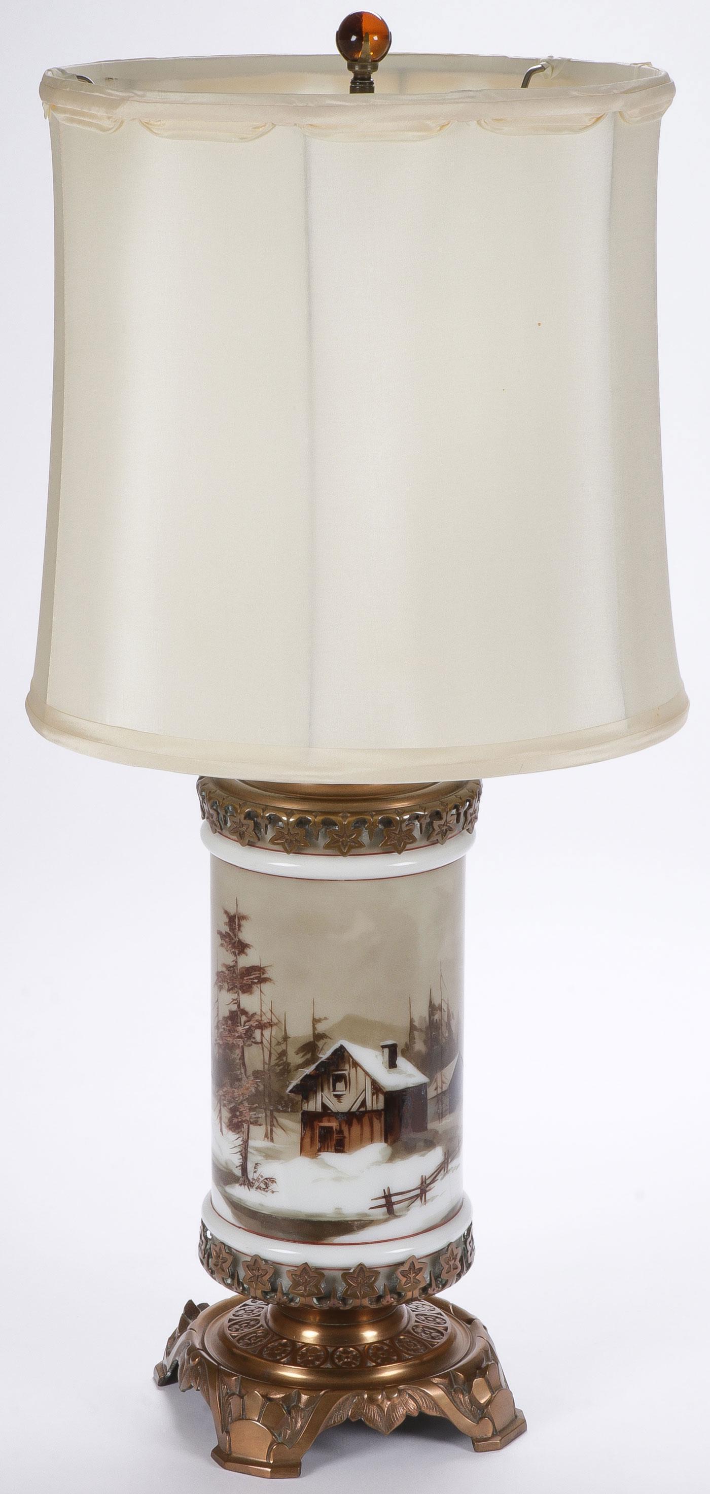 UNIQUE VINTAGE OPAQUE GLASS TABLE LAMP: UNIQUE VINTAGE OPAQUE GLASS TABLE LAMP. The opaque cylindrical glass central column mounted on an ornate cast brass footed base with conforming top, the sides painted with a winter cabin scene, perhap