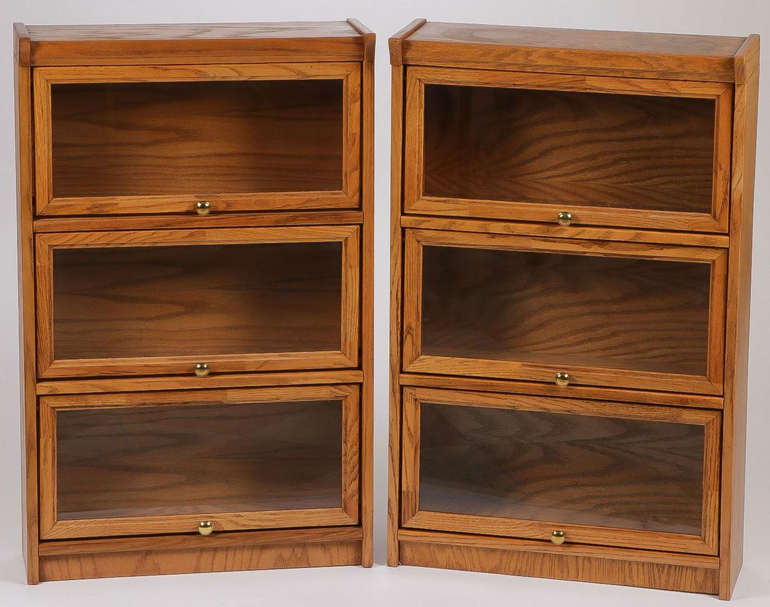 A PAIR OF BARRISTER BOOKCASES: A PAIR OF BARRISTER BOOKCASES. Comprising two three section lawyer or barrister style bookcases of identical rectangular design with three glazed sliding doors at front affixed with brass knobs. Each 