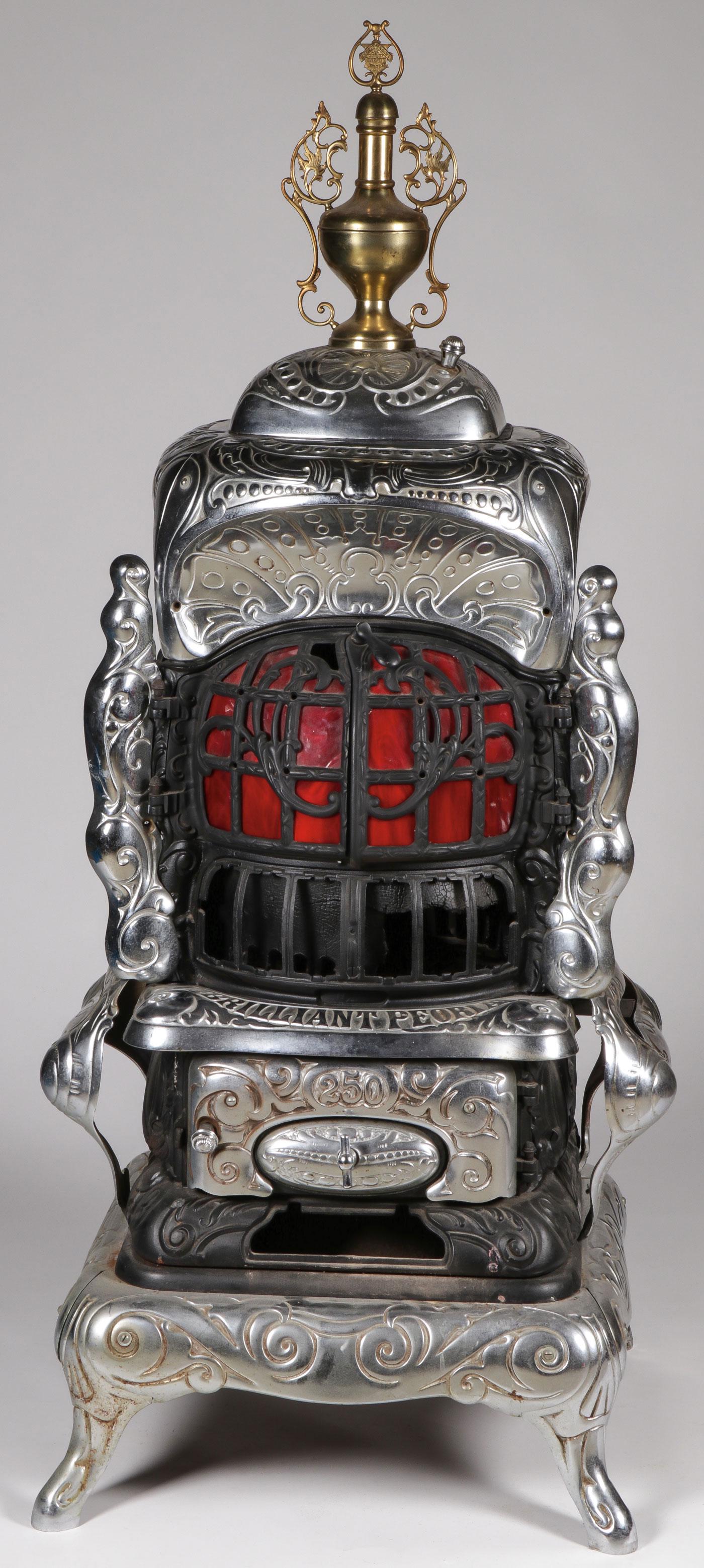 IMPRESSIVE CAST IRON PARLOR STOVE: IMPRESSIVE CAST IRON PARLOR STOVE. Comprising a large and impressive cast iron "pot-belly" parlor stove with nickel-plated elements, red glass inserts, and ornate brass urn-form finial. The front mark