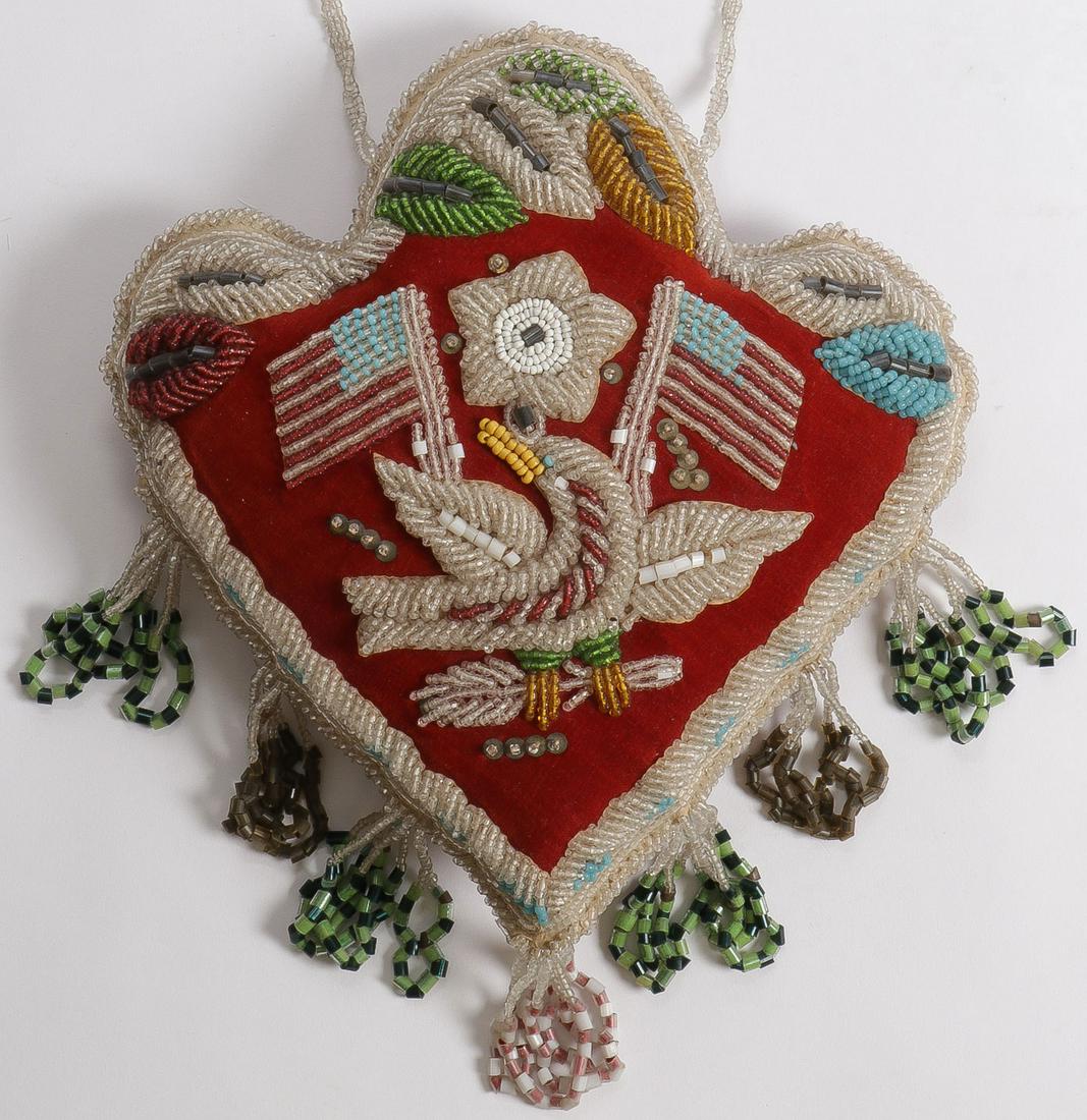 PATRIOTIC IROQUOIS BEADED PILLOW, C. 1900: PATRIOTIC IROQUOIS BEADED PILLOW, C. 1900. Comprising an exceptional padded heart shaped pillow with heavily beaded borders displaying tassels and original beaded suspension loop. The cover beaded wit