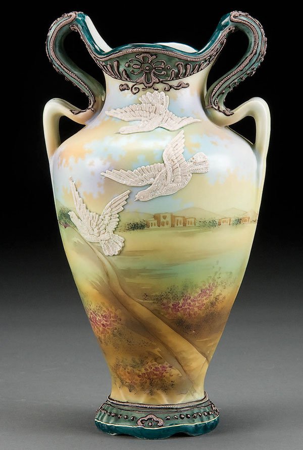 NIPPON MORIAGE SCENIC HANDLED VASE: A VERY FINE HAND PAINTED NIPPON MORIAGE DECORATED SCENIC HANDLED VASE early 20th century, with scene of moriage birds in flight below a scrolled moriage handle and rim. Blue maple leaf mark. Height 9 